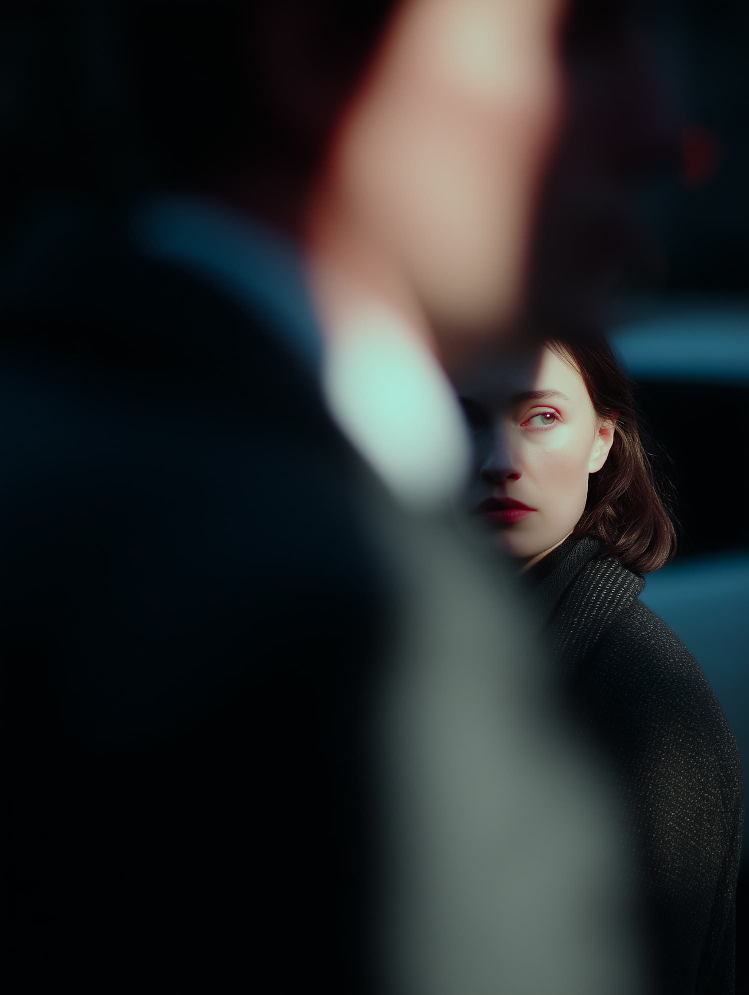 Woman glancing over her shoulder past a blurred figure in deep teal light